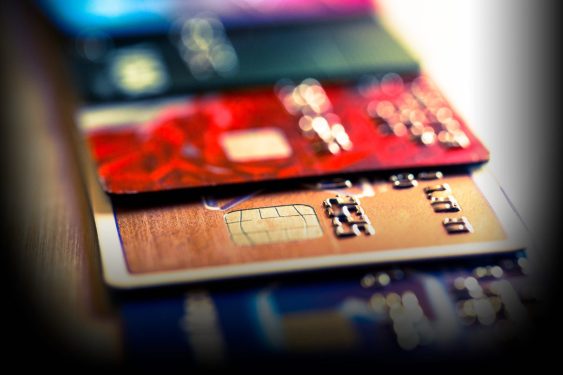 Close-up view of multiple colored credit and debit cards with chips and embossed numbers