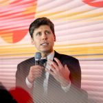 Person speaking at an event with colorful geometric shapes backdrop