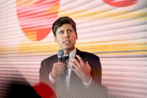Person speaking at an event with colorful geometric shapes backdrop
