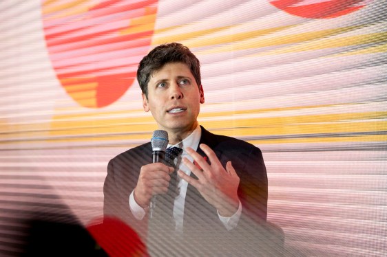 Person speaking at an event with colorful geometric shapes backdrop
