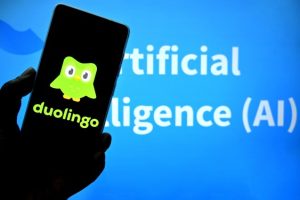 Duolingo logo on smartphone screen with green owl mascot and text 'Artificial Intelligence (AI)' in the background