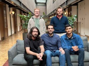 Group of five people posing in a hallway - casual and friendly atmosphere