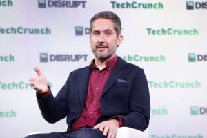 Man at TechCrunch event gesturing on stage with TechCrunch and TC Disrupt logos in background