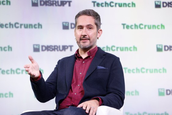 Man at TechCrunch event gesturing on stage with TechCrunch and TC Disrupt logos in background