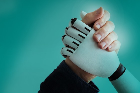 A human hand shaking hands with a robotic or prosthetic hand against a teal background, symbolizing collaboration in a robot-driven world.