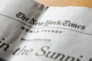 Newspaper section featuring The New York Times with headlines on world trends and news analysis, slightly crumpled paper