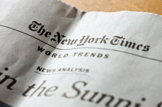 Newspaper section featuring The New York Times with headlines on world trends and news analysis, slightly crumpled paper