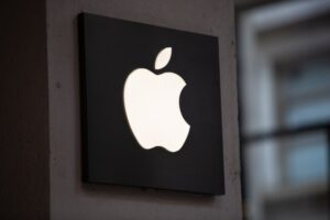 Illuminated Apple logo displayed on a wall, symbolizing Apple's presence in the tech industry amidst AI advancements