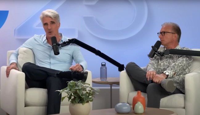 Two people participating in a podcast or interview about Apple's AI plans, with microphones and decorative vases on the table and a plant in the foreground