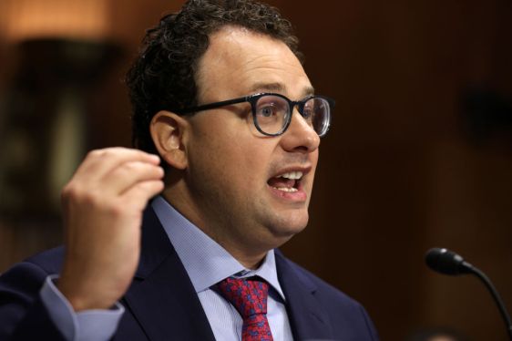 Person speaking at a microphone in formal setting, representing leadership in national security and AI innovation.